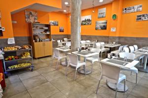 a restaurant with tables and white chairs and orange walls at Hotel Puerto Canteras in Las Palmas de Gran Canaria