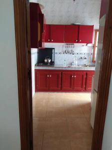 a red kitchen with red cabinets and a tile floor at Superbe appartement chaleureux à 350m de la plage in M'diq