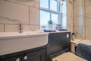 a bathroom with a sink and a tub and a window at Luxurious newly built cottage in central Wivenhoe in Wivenhoe