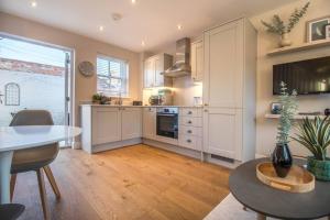 uma cozinha com armários brancos e uma mesa em Luxurious newly built cottage in central Wivenhoe em Wivenhoe