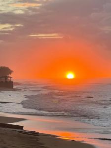 um pôr do sol na praia com um cais no oceano em Aguada Beach Condos em Aguada