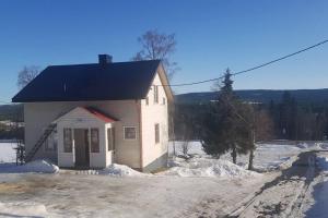 a small white building with a black roof in the snow at Mysigt hus med utsikt över fjäll och älv. in Järpen