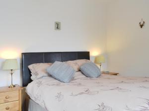sypialnia z łóżkiem z poduszkami i 2 lampami w obiekcie Ard Meanish w mieście Milovaig