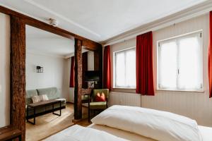 a bedroom with red curtains and a bed and a chair at Hotel-Gasthof Goldener Greifen in Rothenburg ob der Tauber