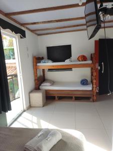 sala de estar con TV y sofá en Suites Malibu, en Arraial do Cabo