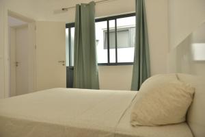 um quarto com uma cama branca e uma janela em Duarte Apartments - Lux em Mindelo