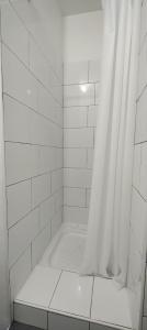 a white tiled shower with a white shower curtain at Bel appartement centre ville. in Blaye