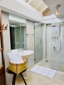 ein Bad mit einem Waschbecken und einer Glasdusche in der Unterkunft Coco Mantra Ilukwehera Estate 