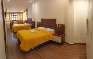 two beds in a hotel room with yellow sheets at Hotel Silva Inn in Cajamarca