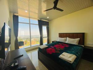 a bedroom with a bed and a desk and a window at Tulips Valley View Resorts in Ooty