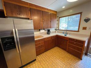 a kitchen with wooden cabinets and a stainless steel refrigerator at Harte's Desire Cabin - Lake, A/C, Arcade + in Twain Harte