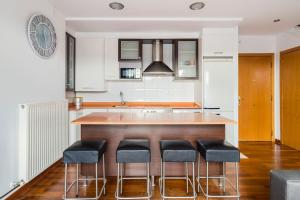 a kitchen with a bar with four stools at Dúplex Surf junto a la playa in Miengo