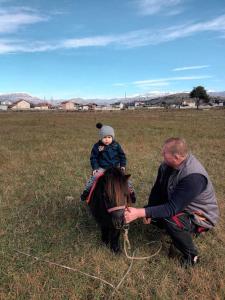 um homem e uma criança num cavalo num campo em Vikendica Komovi em Andrijevica