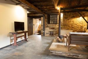 a room with a bench and a table and a television at CASA GRANDE VILAR in Vilar