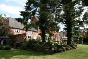 una gran casa de ladrillo con árboles y un patio en Self catering cottage in Market Bosworth, en Market Bosworth