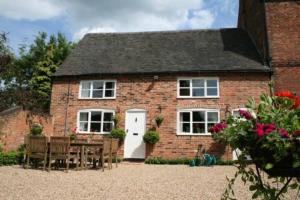 Self catering cottage in Market Bosworth في ماركت بوسوورث: منزل من الطوب مع طاولة وكراسي أمامه