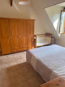 een slaapkamer met een bed, houten kasten en een wieg bij Gîte Fuchsia in Carlux