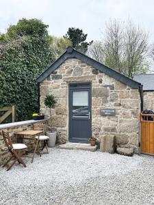 a stone shed with a blue door and a table and chairs at Cosy country getaway, 5 mins from the sea in Penzance