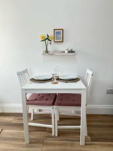 a white table with two chairs and a table with flowers on it at Cosy country getaway, 5 mins from the sea in Penzance