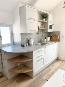 a kitchen with white cabinets and a sink at Cosy country getaway, 5 mins from the sea in Penzance