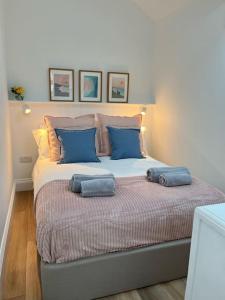 a bed with two blue pillows on top of it at Cosy country getaway, 5 mins from the sea in Penzance