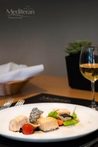 a white plate with food and a glass of wine at Hotel Mediteran in Zadar