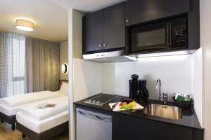a small kitchen with a sink and a microwave at Aparthotel Adagio access München City Olympiapark in Munich +14 photos