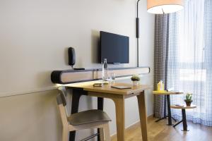 a room with a desk with a television on it at Aparthotel Adagio access München City Olympiapark in Munich
