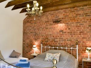 a bed in a room with a brick wall at Cornflower Cottage Ukc1897 in Dogdyke