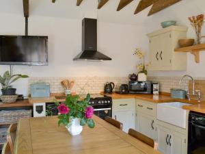 a kitchen with a table with a vase of flowers on it at Cornflower Cottage Ukc1897 in Dogdyke