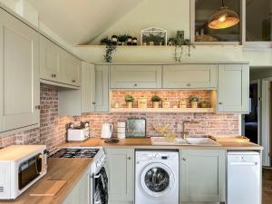 a kitchen with white cabinets and a brick wall at Talltrees - Uk42842 in Uplowman