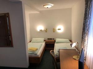 um quarto com 2 camas, uma secretária e uma mesa em Unterkunft zu Krone em Hofheim in Unterfranken