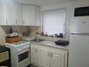 a kitchen with white cabinets and a sink and a stove at Vikendica Lep pogled in Rtanj