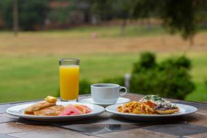 a table with two plates of food and a glass of orange juice at Hotel & Glamping Huasca Sierra Verde in Huasca de Ocampo
