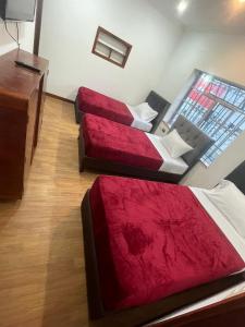 a room with two beds and a dresser at Hotel Casa Morada FC in Bogotá