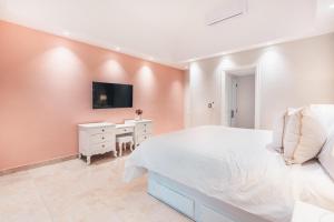 a bedroom with a white bed and a tv on a wall at Enjoy this modern pet and family friendly villa B6 in Punta Cana