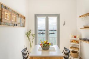a dining room with a table and a view of the water at Yialos Rooms in Piso Livadi