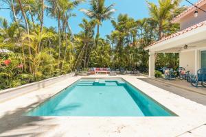 a swimming pool in the backyard of a house with palm trees at Enjoy this modern pet and family friendly villa B6 in Punta Cana
