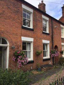 a red brick house with white windows and flowers at Halday in Stafford