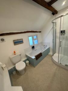 a bathroom with a tub and a toilet and a sink at 36 Heritage House in Kington