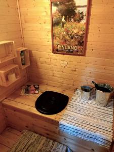 a wooden cabin with a black lid in a room at Mökki järven rannalla mäntymetsässä in Forssa