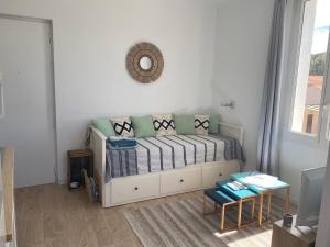a living room with a bed with pillows and a mirror at Studio le Monroe les pieds dans l'eau 10 m de la mer in La Seyne-sur-Mer