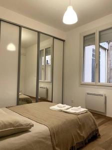 sypialnia z dużym łóżkiem z dwoma ręcznikami w obiekcie Appartement Les Halles Narbonne w mieście Narbona