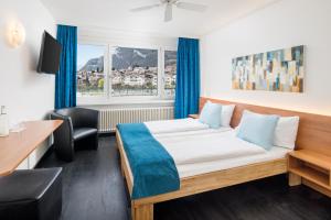 Cette chambre comprend un lit, un bureau et une fenêtre. dans l'établissement Hotel Merkur - West Station, à Interlaken