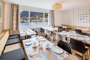 ein Restaurant mit Tischen und Stühlen und einem großen Fenster in der Unterkunft Hotel Merkur - West Station in Interlaken