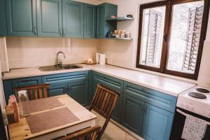 a kitchen with blue cabinets and a table and a sink at Holiday house Zlata in Banjol