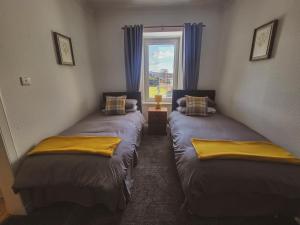 two twin beds in a room with a window at THE EARN HOTEL in Bridge of Earn