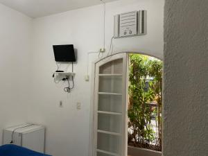 a room with a door with a television and a window at Pousada Praia do Tombo in Guarujá