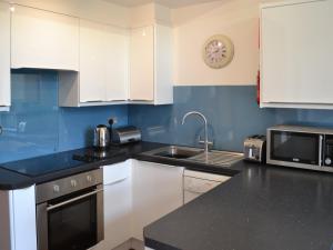 a kitchen with white cabinets and a sink and a microwave at Sunset in St Austell