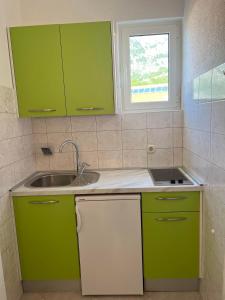 a kitchen with green cabinets and a sink at Apartments Jurisic in Baška Voda